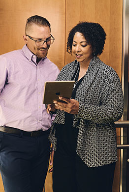 Smiling people on ipad - easily manage workers' comp insurance online. 